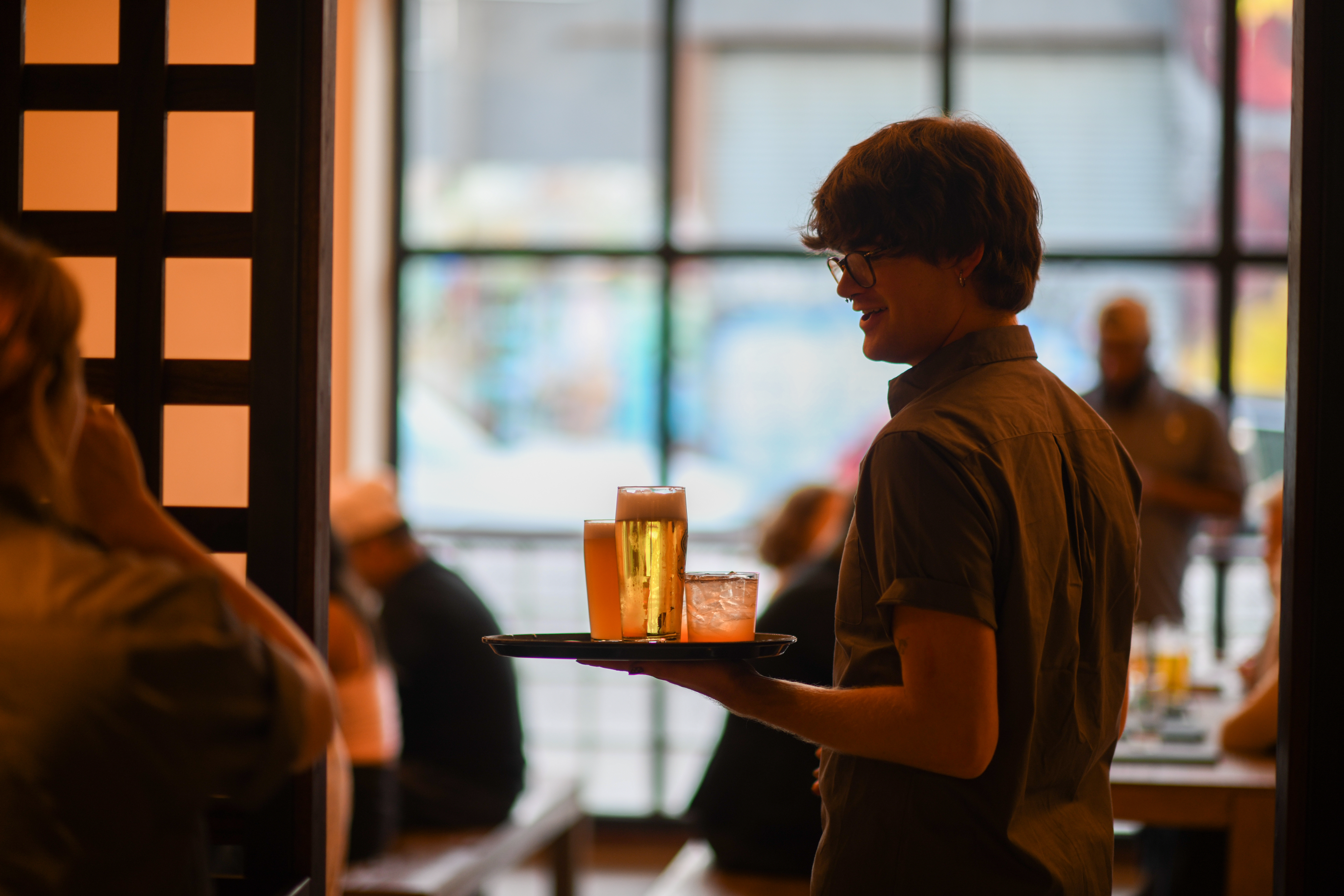 Server carrying a tray of drinks in the Eckhart Beer Co. biergarten